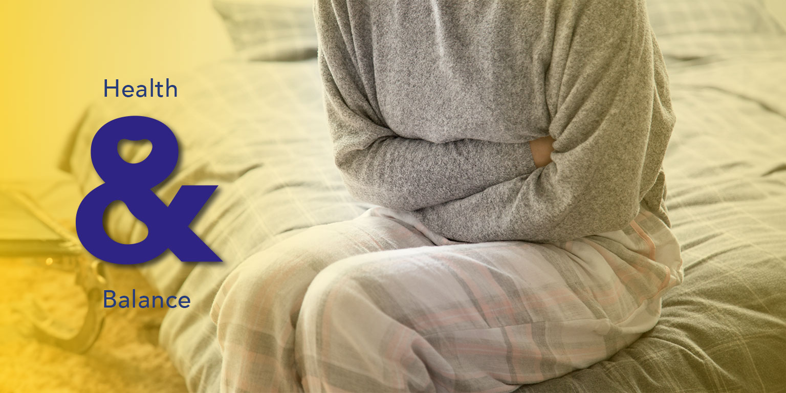 Woman experiencing PMS symptoms and holding her lower abdomen